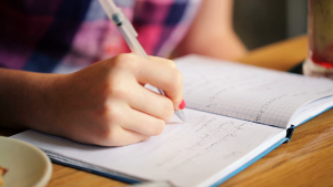 Teen writing in notebook