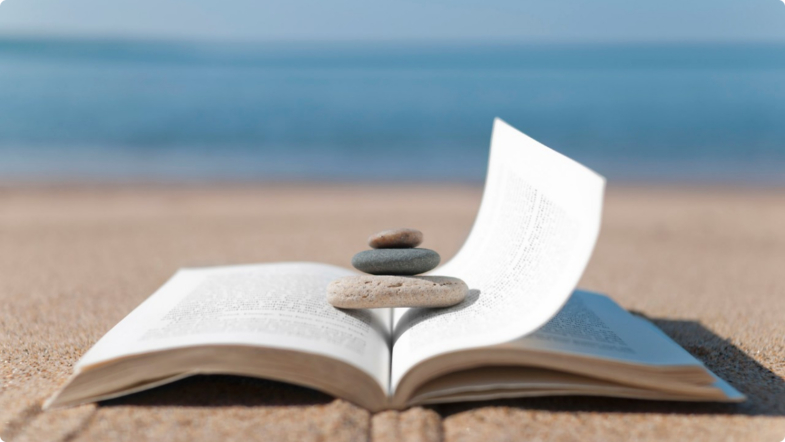 Open book with three skipping stones holding it open against beach backdrop