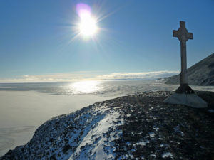 The gravestone gleams in the sun reflecting off the endless ice.