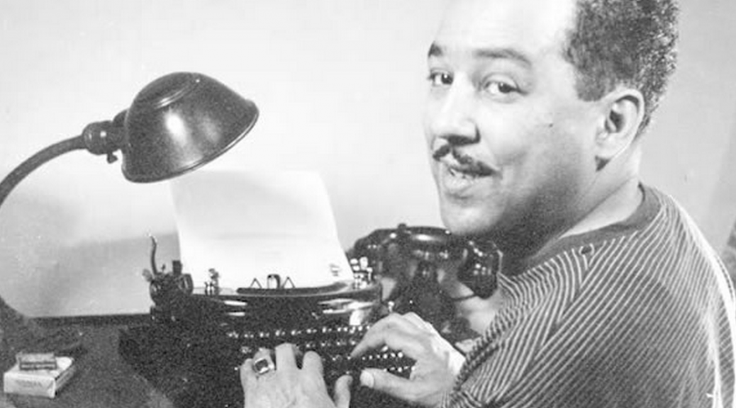 Langston Hughes happily at a typewriter