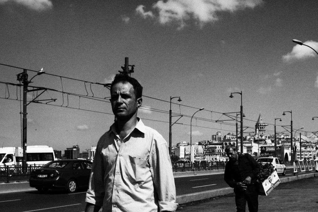 Jack Kerouac on the road, walking forward under the sky in a black and white photo