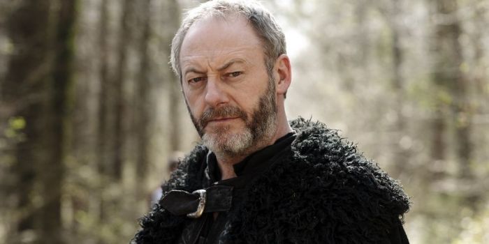 Liam Cunningham in character looking at camera, in forest