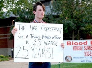 A person holds up a sign reading "The life expectancy of a trans woman of color is 25 years! 25 years!"