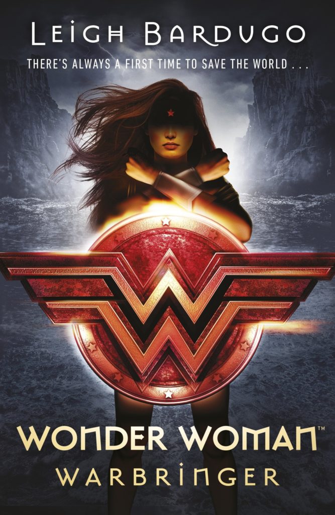 Wonder Woman stands with her arms crossed before a raging sea