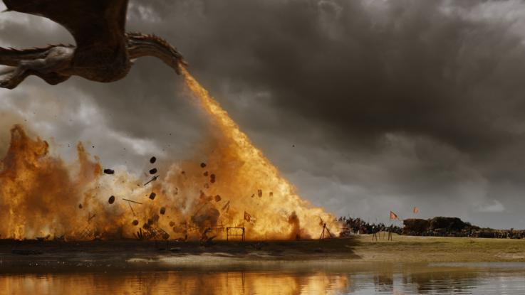 A dragon flies low over a battlefield, roasting soldiers with its flaming breath