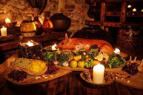 A lavish feast including a pig, vegetables, bread, and potatoes