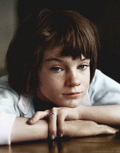 Scout Finch, a young girl leans on the table with her elbows 