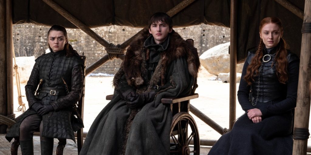 Arya, Bran, and Sansa sit on three chairs in a row