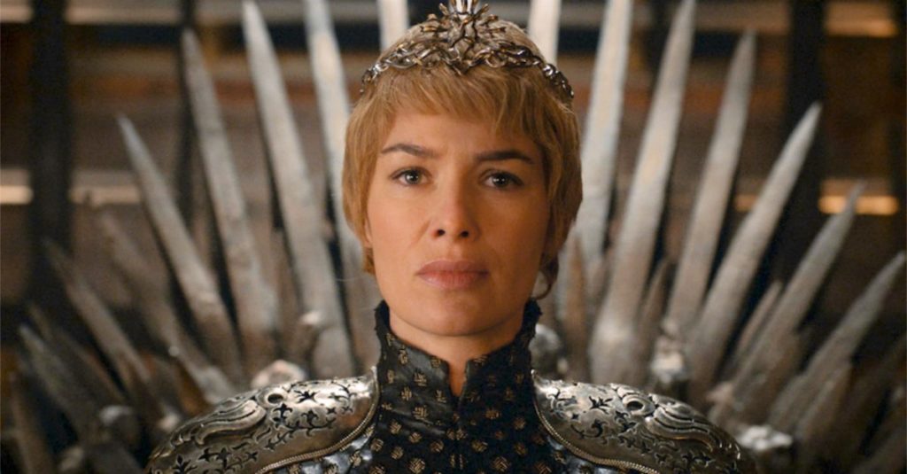 Cersei sits on the Iron Throne, wearing a crown and her queenly dress