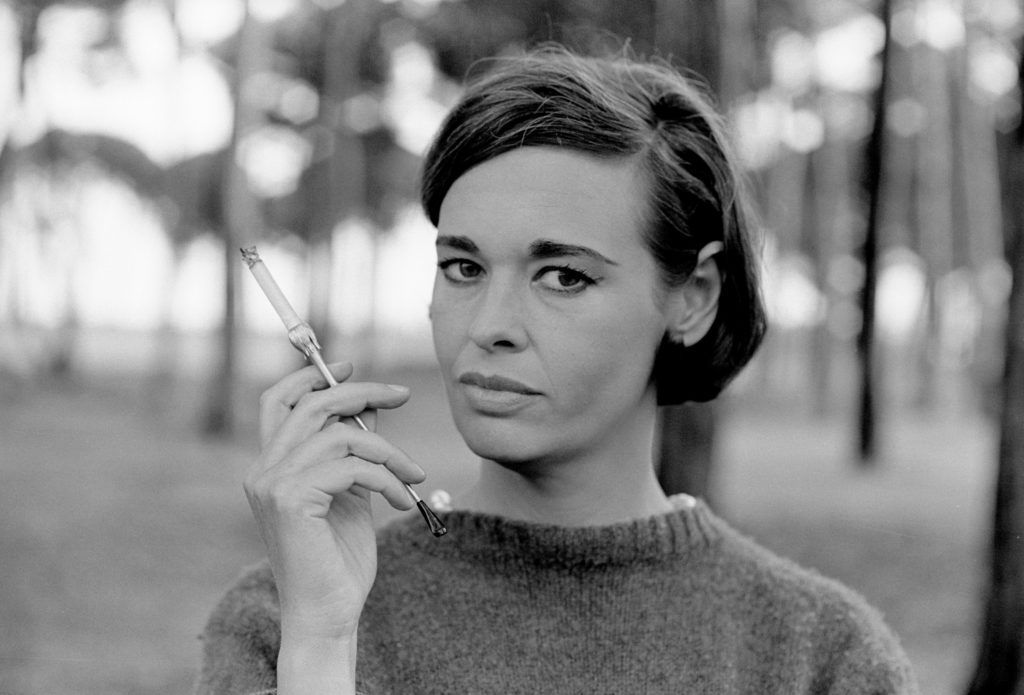 Gloria Vanderbilt holds a cigarette in a black and white photo