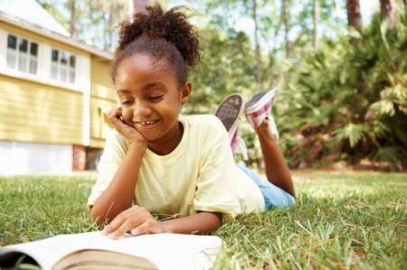 Young girl reading outside during summer