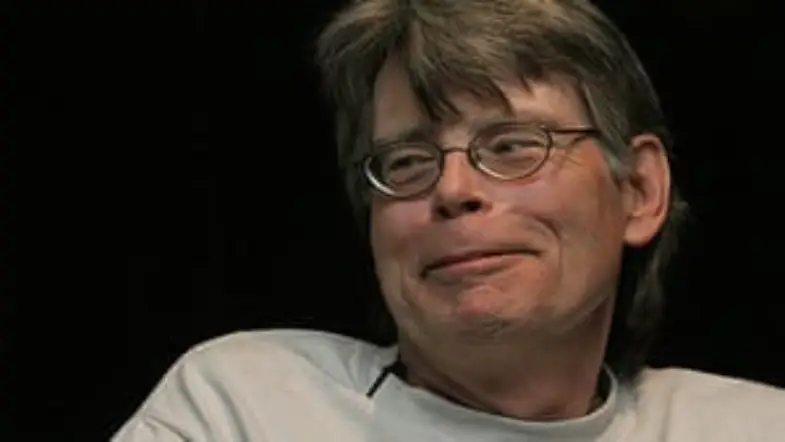Stephen King smiling against black background