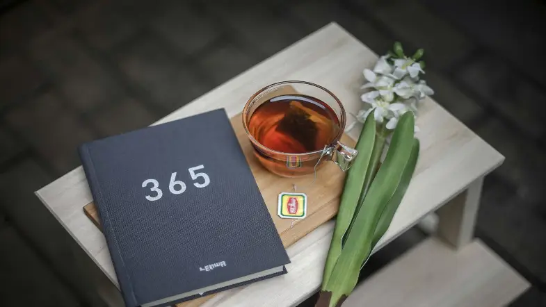 Blue 365 book next to tea and white flowers on table