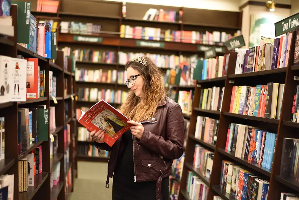 Image of a woman standing in a bookstore looking through a book