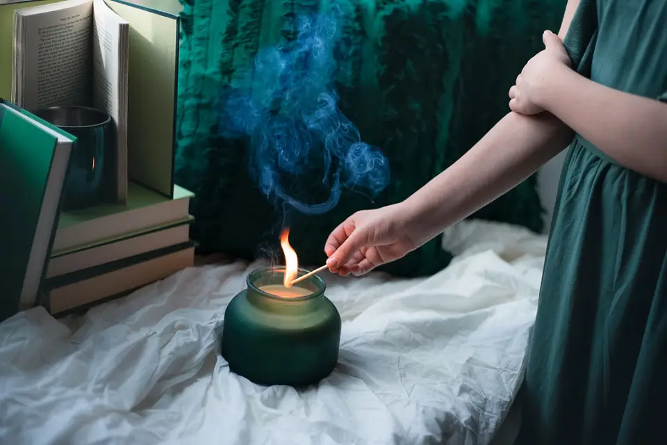 Image of a woman lighting a candle with smoke rising from the candle