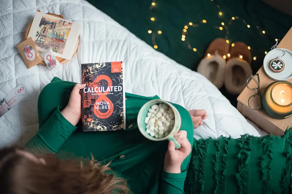 Top down looking at a book and mug with a woman holding them