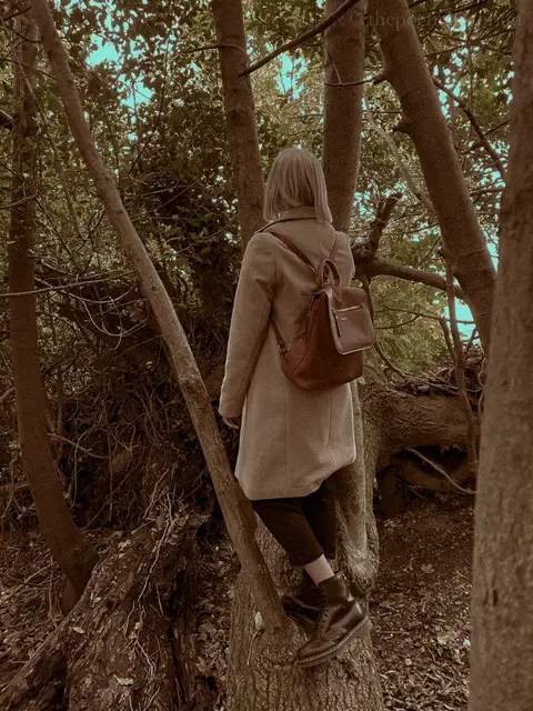 Image of a woman standing between two tree trunks in a forest