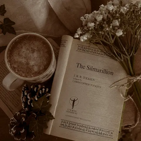 Image of an open book on a desk next to a cup of coffee and some white flowers