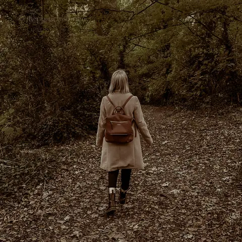 Image of a woman in a forest facing way from the camera