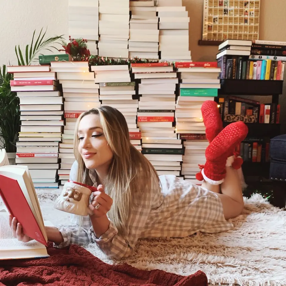 Image of a woman reading a book while sipping from a mug 