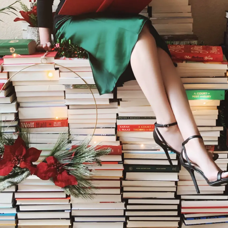 Image of a woman sitting on several stacks of books