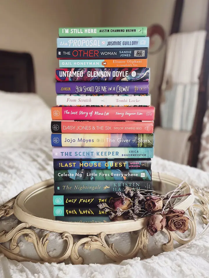 A stack of 15 books on a side table