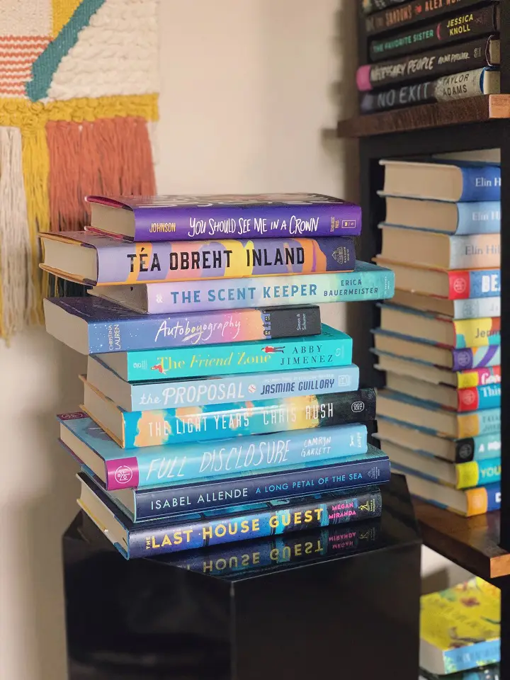 Image of a stack of books on a black table next to a bookshelf